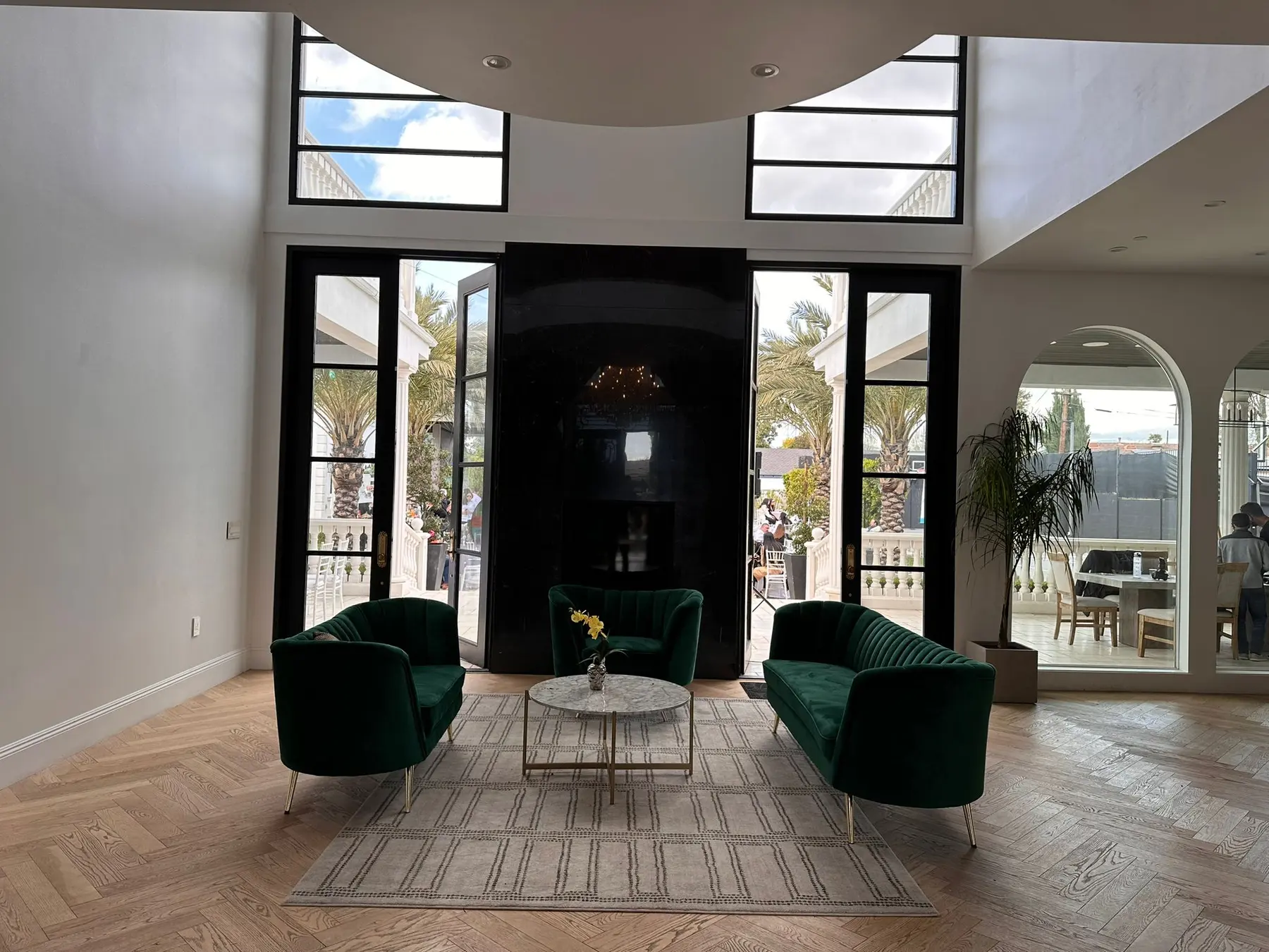 Double-height living space with a polished black stone feature wall, steel-framed glazing, and herringbone oak flooring